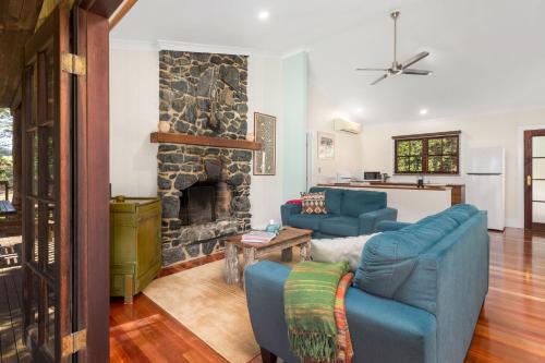 a living room with two blue couches and a stone fireplace at Friday Creek Retreat in Coffs Harbour
