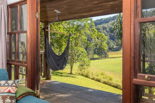 a hammock on a porch with a view of a field at Friday Creek Retreat in Coffs Harbour