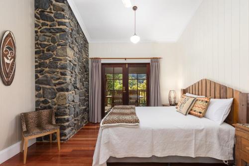 a bedroom with a bed and a stone wall at Friday Creek Retreat in Coffs Harbour