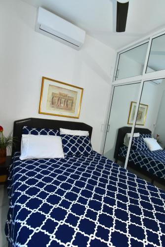 a bedroom with a blue and white bed with a mirror at Rosil Place in San Felipe de Puerto Plata