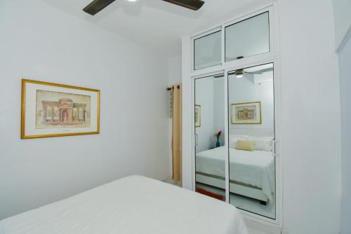 a white bedroom with a bed and a mirror at Rosil Place in San Felipe de Puerto Plata