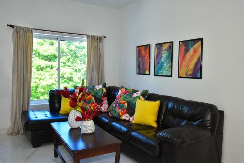 a living room with a black leather couch and a table at Rosil Place in San Felipe de Puerto Plata