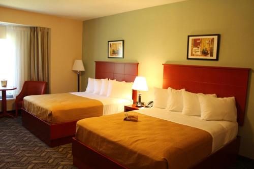 a hotel room with two beds and a table with a chair at Quality Inn Southampton in Southampton