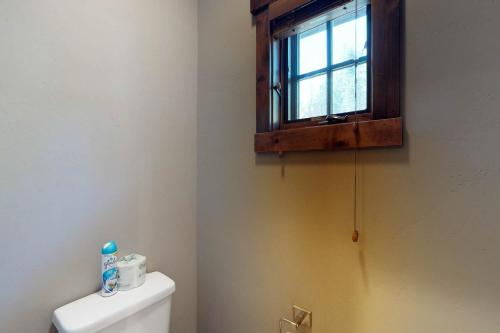 a bathroom with a toilet with a window on the wall at Tamarack Cottage in Donnelly