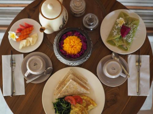 乌布Kampung Sari Homestay的一张木桌，上面摆放着食物盘子