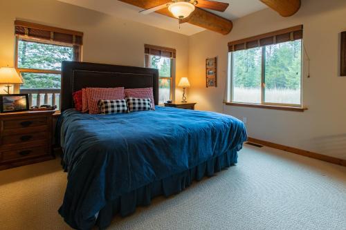 1 Schlafzimmer mit einem Bett mit blauer Decke und 2 Fenstern in der Unterkunft Lake 5 Cabin in West Glacier
