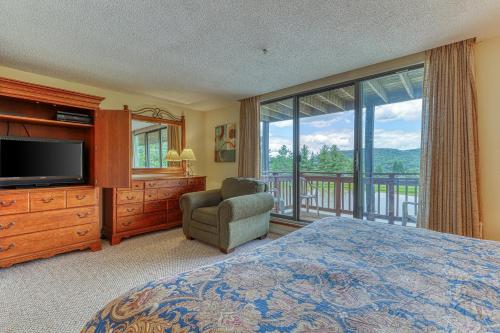 une chambre avec un lit et une télévision et un balcon dans l'établissement Snowlake D-25, à Sugar Mountain