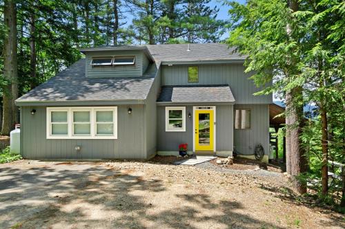 a gray house with a yellow door and trees at New England Treasure in North Conway