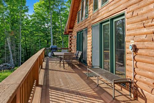 a deck with benches and a grill on a house at Private Franconia Log Cabin in Franconia