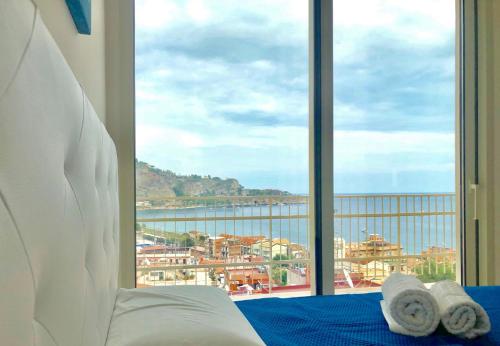 a bedroom with a bed with a view of the ocean at Taormina Wonderful Solarium in Giardini Naxos
