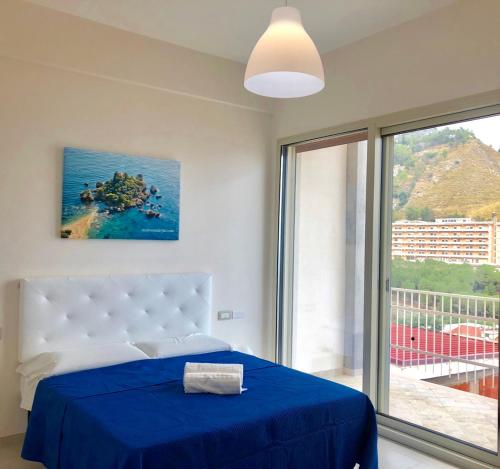een slaapkamer met een bed met blauwe lakens en een raam bij Taormina Wonderful Solarium in Giardini Naxos