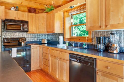 a kitchen with wooden cabinets and a black dishwasher at Private Franconia Log Cabin in Franconia