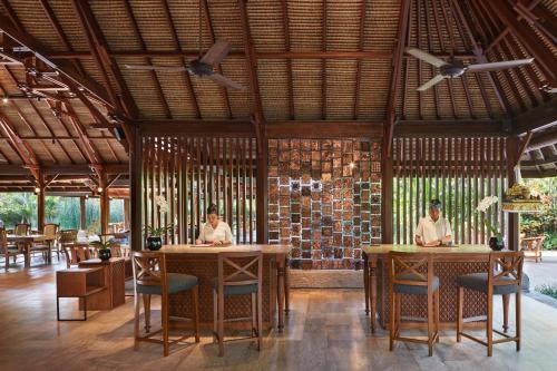 two people sitting at tables in a restaurant at Hyatt Regency Bali in Sanur
