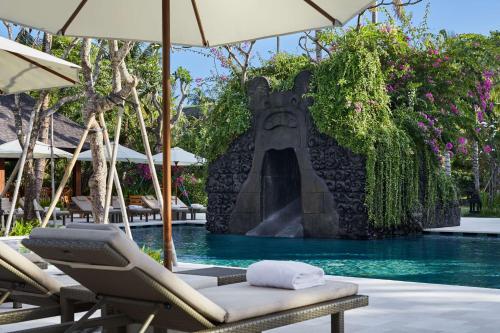 a pool with chairs and an umbrella and a swimming pool at Hyatt Regency Bali in Sanur