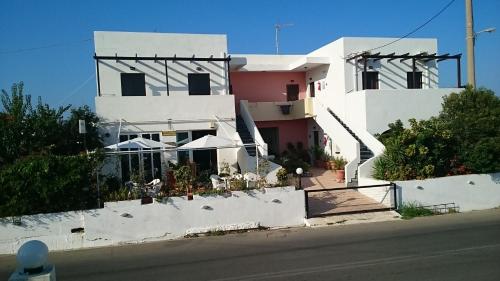 a white building with tables and umbrellas in front of it at Iliaktida Apartments in Kolymvari