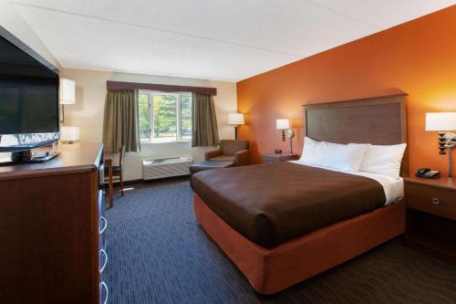 a hotel room with a bed and a flat screen tv at AmericInn by Wyndham Silver City in Silver City