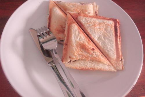 a white plate with two slices of bread and a fork at Pintu Biru Hostel in Wamena