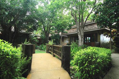 a wooden walkway leading to a house with trees at Superkids Resort in Phitsanulok