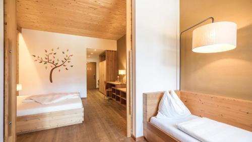 a room with two beds and a lamp and a desk at Biohotel theiner's garten in Lana