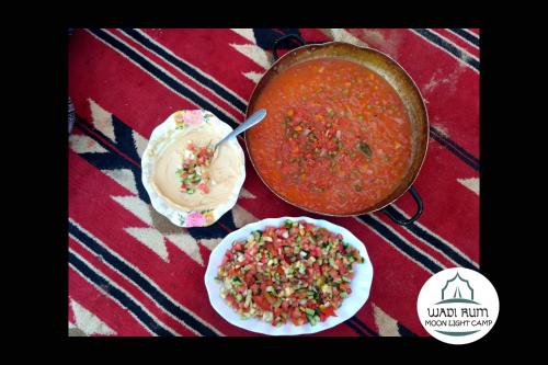 a table with a pot of soup and a plate of food at Wadi Rum Moon Light Camp in Wadi Rum