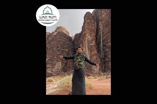a man standing in front of some rock formations at Wadi Rum Moon Light Camp in Wadi Rum