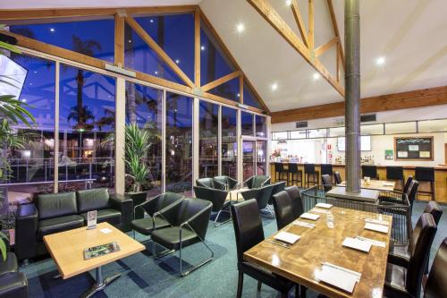 een restaurant met tafels en stoelen en grote ramen bij Mildura Inlander Resort in Mildura