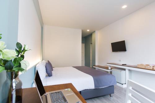 チェンマイにあるAt the Train Chiang Mai Hotelのベッド1台、ノートパソコン1台、デスクが備わる客室です。