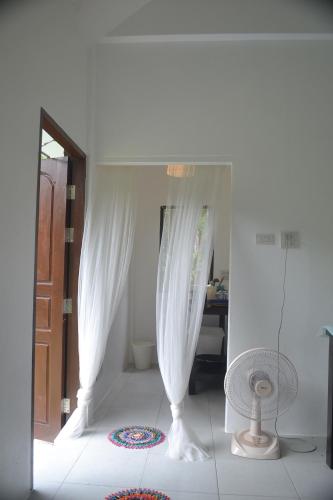 a bathroom with white curtains and a room with a door at Homebar in Ko Chang