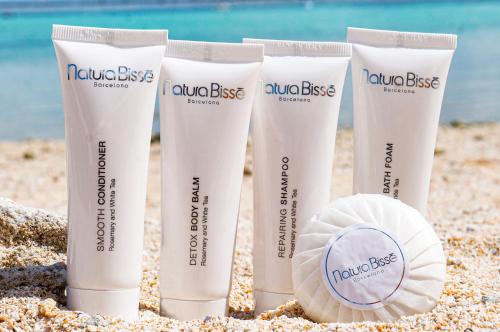 a group of four sunscreen bottles on a sandy beach at The Tsubaki Tower in Tumon