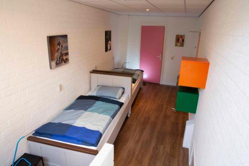 een kleine slaapkamer met een bed en een roze deur bij ut Hen Hoes in Swalmen