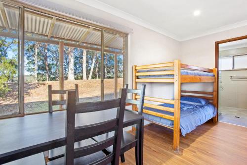 a dining room with two bunk beds and a table at Braeside Cabin Three Parsonsia in Central Tilba