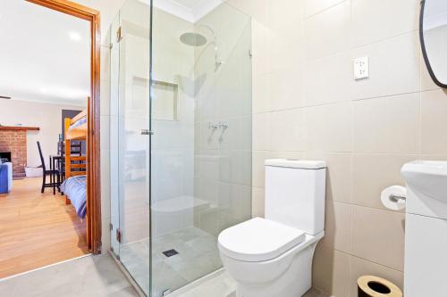 a bathroom with a toilet and a glass shower at Braeside Cabin Three Parsonsia in Central Tilba