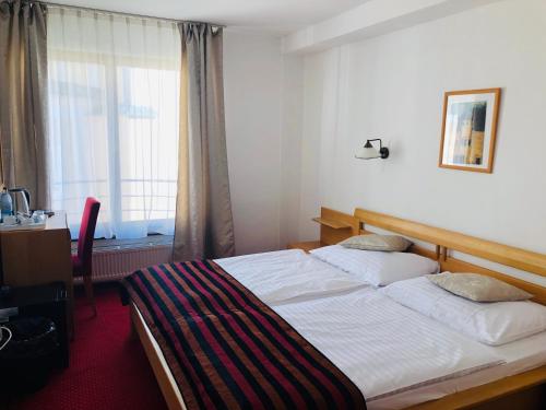 a bedroom with a bed and a desk and a window at Hotel & Penzión Grand Matej in Banská Štiavnica