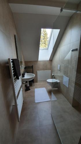 ein Bad im Dachgeschoss mit einer Dusche und einem Waschbecken in der Unterkunft Apartmánový dom Lúčky 188 in Demänovská Dolina