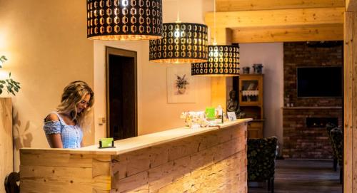a woman standing at a bar in a room at Hotel Berghof in Nesselwängle