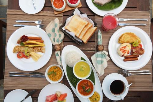 a wooden table topped with plates of breakfast food at Jetwing Villa 700 in Bentota