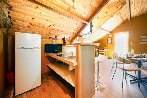 a kitchen with a white refrigerator and a table at Le jardin des Biches in Somme-Leuze