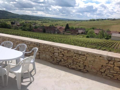 d'une terrasse avec une table et des chaises ainsi qu'un mur en pierre. dans l'établissement Au Pied des Vignes, à Santenay