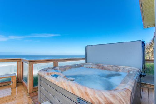 a hot tub on a balcony with a view of the ocean at Gleneden BeachFront Getaway in Lincoln Beach