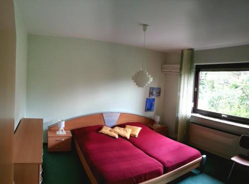 a bedroom with a red bed with a window at Fewo-Seefeld in Norderaussendeich