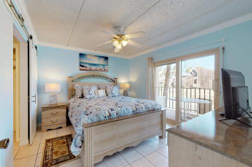 a bedroom with a bed and a television and a balcony at Beachview Condominiums: #204 in South Padre Island