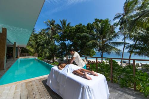 a woman laying on a bed next to a pool at Kiha Beach in Dharavandhoo