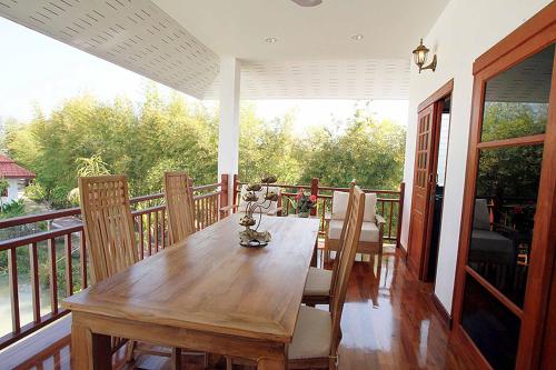 a wooden dining room table and chairs on a balcony at Jasmine Hills Lodge in Doi Saket