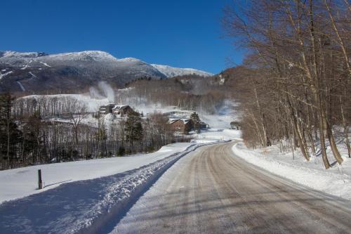 a snow covered road with trees and houses on it at Cozy Stowe Retreat in Stowe
