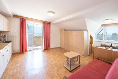 a large kitchen with red curtains and a red couch at Ferienwohnungen Reiterer in Appiano sulla Strada del Vino