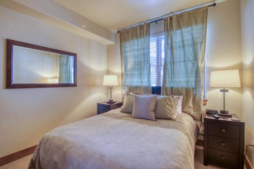 a bedroom with a bed with two lamps and a window at The Cache in West Village in Copper Mountain