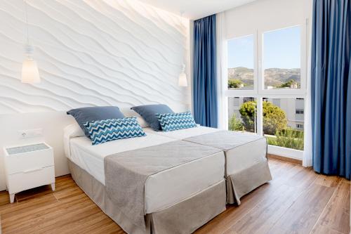 a bedroom with a bed with blue pillows and a window at Alcossebre Sea Experience in Alcossebre