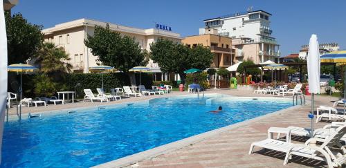 a person in a swimming pool with chairs and umbrellas at Hotel Perla in Senigallia