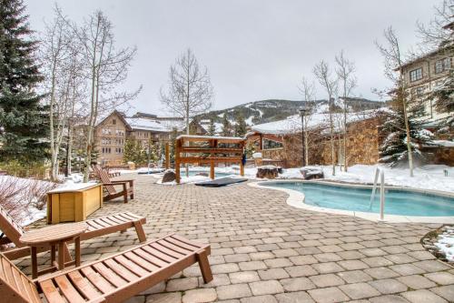 a patio with benches and a pool in the snow at Passage Point 422 in Copper Mountain