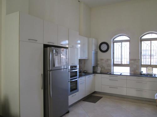 una cucina con armadi bianchi e frigorifero in acciaio inossidabile di Beautiful 8 Bedrooms Villa in the Heart of Nahlaot a Gerusalemme
